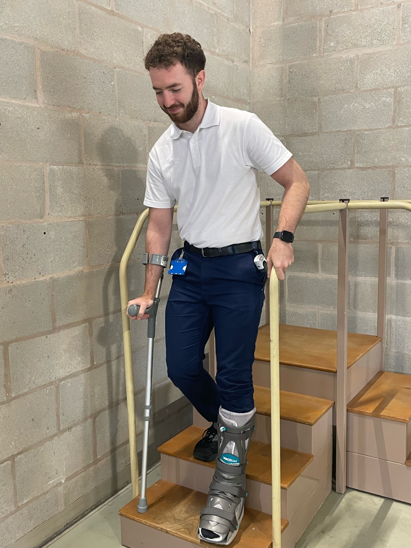 Image of a person demonstrating going downstairs with one crutch when there is a handrail