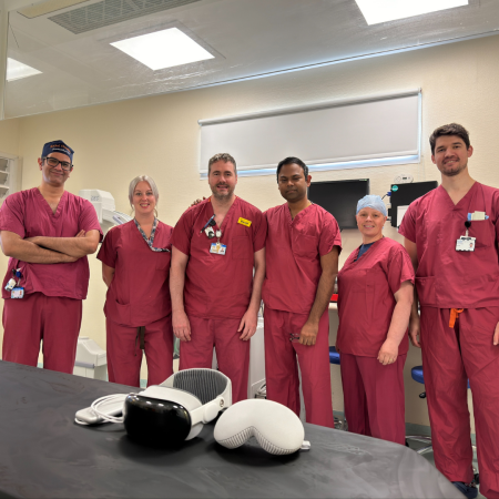 six people in scrubs standing next to a AR headset